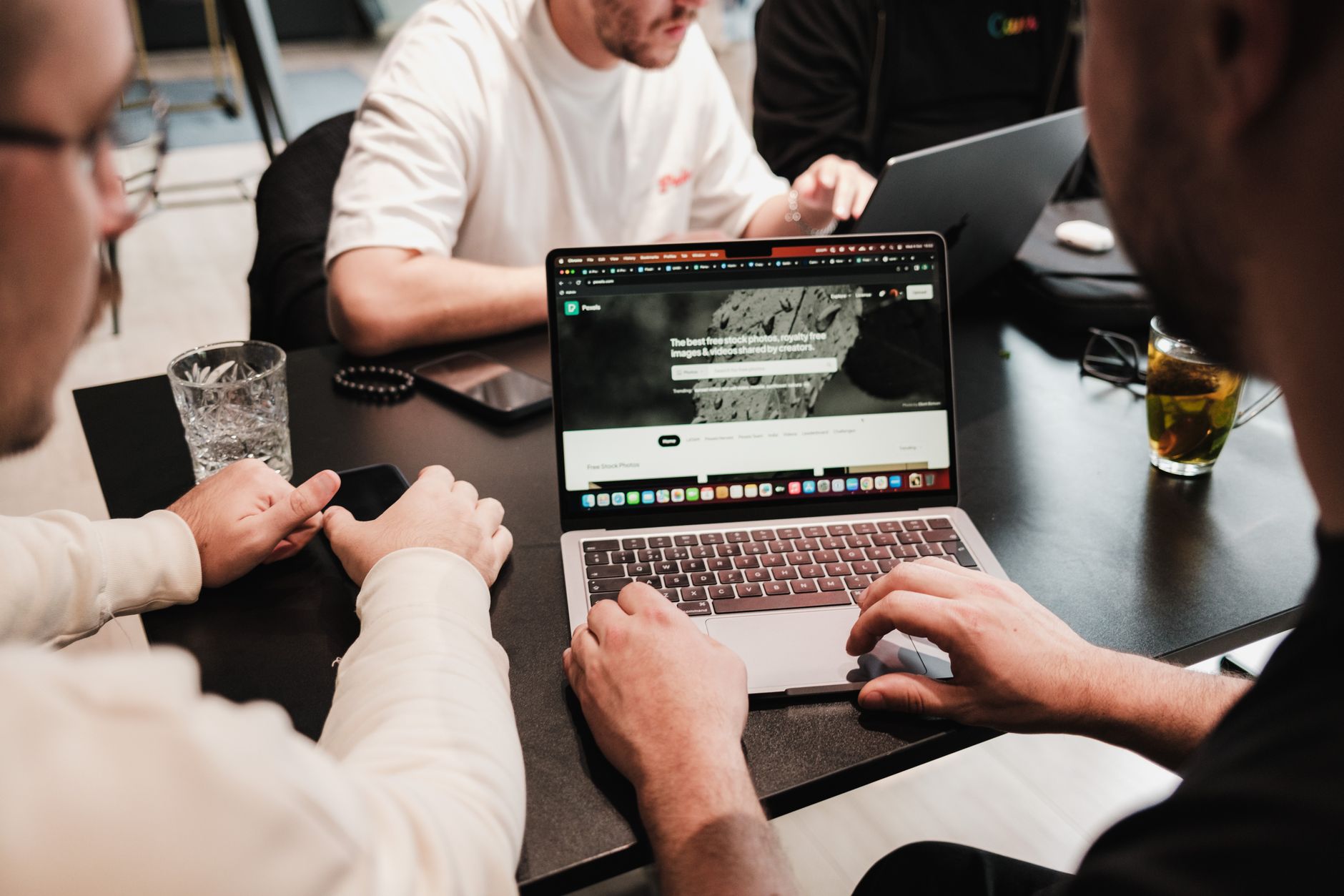 A small team collaborating on laptops around a table.